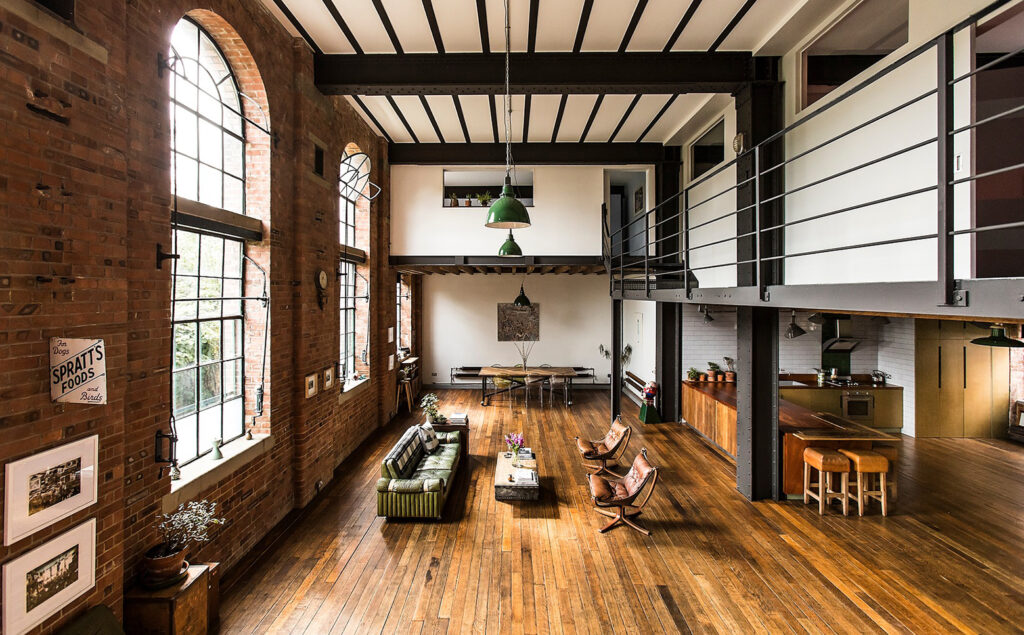 Warehouse conversion with beams, mezzanine floor, arched windows and exposed brick.